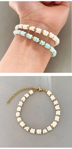 Close-up of elegant handmade shell bead bracelet with white ceramic beads and gold chain