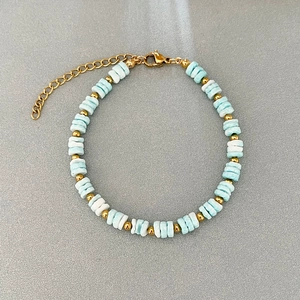 Elegant beaded bracelet with blue marble stones and gold spacers on a textured grey surface