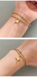 Macro detail of a double-layer gold star pendant bracelet with bead chain on model wrist