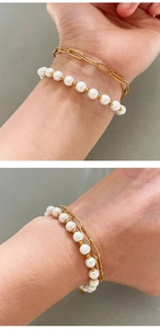Detail of bohemian double-layered gold paperclip link and pearl bead bracelet on wrist