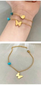 Detail of gold chain bracelets featuring heart and butterfly charms with turquoise beads