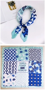 Flat lay of a 70cm silk scarf with tropical leaf prints and geometric patterns