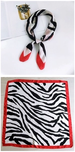 Detail view of 70cm square silk scarf with zebra print and vibrant red border accents