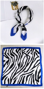 Detail of zebra pattern square silk scarf with bright blue border on wooden surface