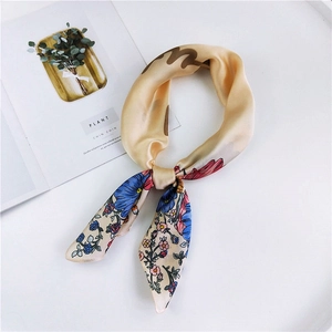 Champagne floral silk scarf tied in a loop on a white tray with minimalist plant card