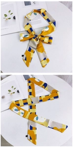 Détail d'un foulard en soie à motifs géométriques avec étiquette sur marbre blanc