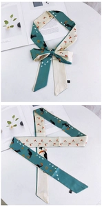 Détail d'un foulard en soie bleu et beige avec imprimés toucan et cerise en nœud