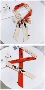 Détail d'un foulard en soie twilly rouge et blanc avec motifs toucan et cerise en noeud