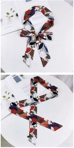 Détail macro d'un foulard en soie fleurie de 155 cm noué en nœud sur un bureau