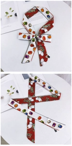 Vue détaillée du motif papillon rouge et gemmes colorées sur ce long foulard en soie