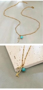 Detail of gold flower necklace with turquoise bead on a white textured background