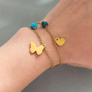 Gold-plated heart and butterfly charm bracelet with turquoise stones on female wrist