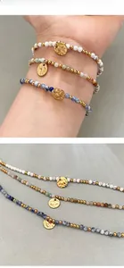 Détail de bracelets à perles trois pièces avec pendentifs dorés en relief de style bohème