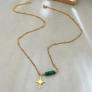 Collier étoile doré avec pendentif pierre verte et chaîne perlée sur fond gris