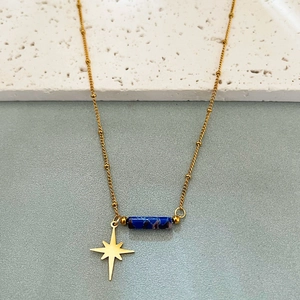 Collier à perles dorées avec pilier de pierre bleue et étoile sur fond de pierre