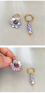 Macro detail of asymmetric blue floral ceramic bead earrings with gold stainless steel