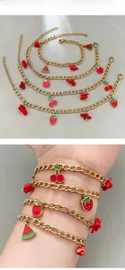Detail view of golden fruit charm bracelet with red strawberry and cherry pendants
