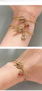 Vue détaillée de deux bracelets trombone dorés avec breloques cerise en cristal et fermoir OT