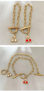 Détail du bracelet chaîne trombone doré avec pendentif cerise et fermoir en T
