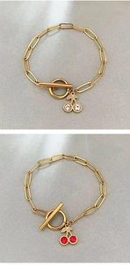 Détail du bracelet trombone doré avec fermoir OT et breloques cerise en pierres colorées