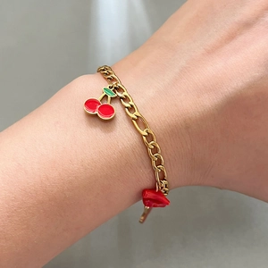 Gold stainless steel Figaro chain bracelet featuring red cherry and heart pendants