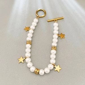Baroque freshwater pearl bracelet with gold star charms and toggle clasp on grey fabric