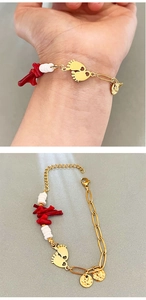 Detail of gold bracelet with red coral, white beads, and tiny footprint charms