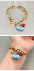Détail du bracelet doré à double couche avec breloques étoile de mer et fermoir à bascule