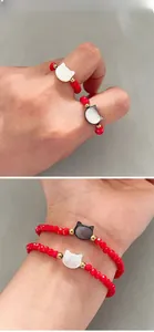 Detail of red beaded cat charm bracelet and ring set with golden spacers on wrist