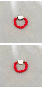 Detail of red beaded stretch rings with silver and white cat-shaped center charms
