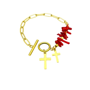 Gold OT clasp bracelet with red irregular beads and double cross charms on white backdrop