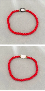 Macro detail of red beaded bracelets with cat-shaped shell charms and gold beads