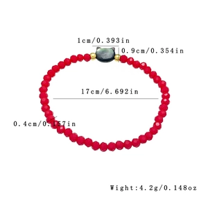 Elastic beaded bracelet with red faceted beads and black owl pendant with gold accents
