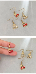 Detail shot of elegant cherry-shaped rhinestone earrings with gold leaves and metal hooks