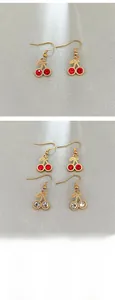 Macro view of crystal cherry earrings featuring red and white rhinestones on gold hooks