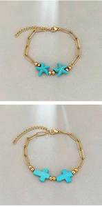 Dettaglio di bracciali a catena dorata con ciondoli a stella marina e croce in turchese blu