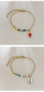 Détail du bracelet en acier doré avec perles œil de chat et breloques coquillages