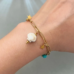Gold chain bracelet with stars, white seashell and turquoise beads on wrist