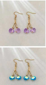Close-up of teardrop crystal pendants in purple and iridescent blue with gold hooks