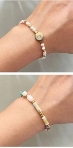 Détail de bracelets en perles d'eau douce avec perles dorées 18K et médaille religieuse