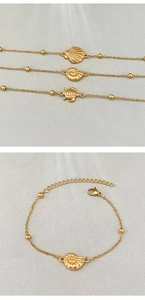 Detail of vintage gold sea shell, conch, and turtle pendants on beaded metal bracelets
