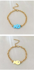 Macro detail of 18k gold plated chain bracelets with blue and yellow enamel fish charms