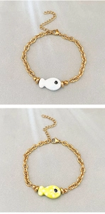 Detail of fish charms in white and yellow enamel on 18k gold plated stainless steel bracelet