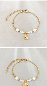 Detail of gold beaded bracelet with pearl accents and sun pendant on textured background