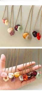 Détail de pendentifs fleurs en acrylique coloré sur chaînes dorées montrant la taille