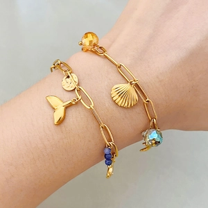 Golden ocean series chain bracelet with fish tail and shell charms worn on wrist