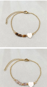 Detail of heart shell pendant and natural stone beads on gold beaded chain bracelets