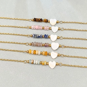 Golden chain bracelets with natural stone beads and shell heart pendants on velvet