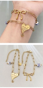 Macro detail of 18k gold plated bracelets with heart and bow pendants on grey background