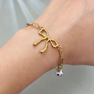 18k gold plated stainless steel bow bracelet with a vintage blue floral porcelain bead